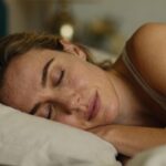 Jeune femme européenne dormant profondément dans un lit, éclairée par une lumière naturelle douce