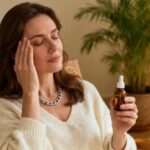 Femme européenne détendue utilisant des granules homéopathiques pour soulager son stress dans un intérieur chaleureux