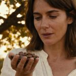 Femme européenne tenant des graines de griffonia simplicifolia dans une lumière naturelle, texture réaliste